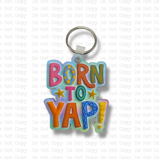 Custom-shaped contoured MDF wood sublimation keychain blank kit featuring a colorful retro bubble letter design with the text Born To Yap!, shown with keyring hardware.