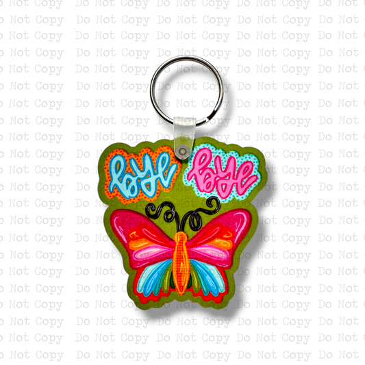 Custom-shaped contoured MDF wood sublimation keychain blank kit featuring a colorful retro doodle style butterfly with text that says bye bye, shown with keyring hardware.